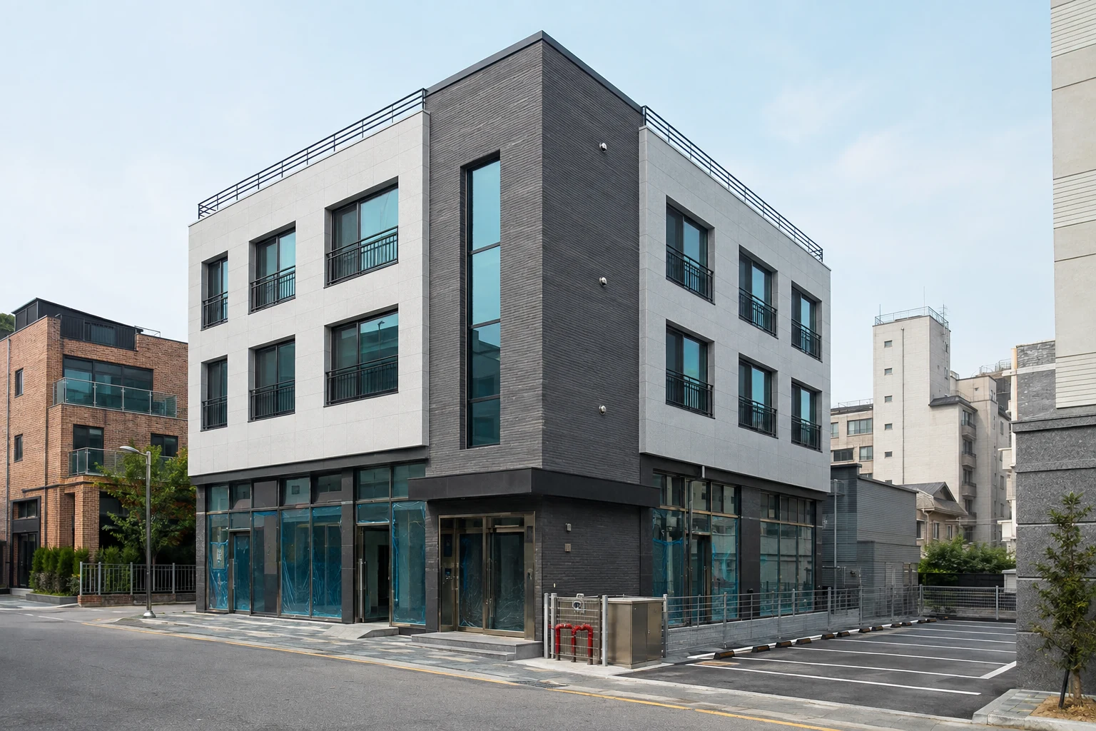 준공 직전의 신축 근린생활·주거 복합 건물과 출입구, 주차 공간이 보이는 전경